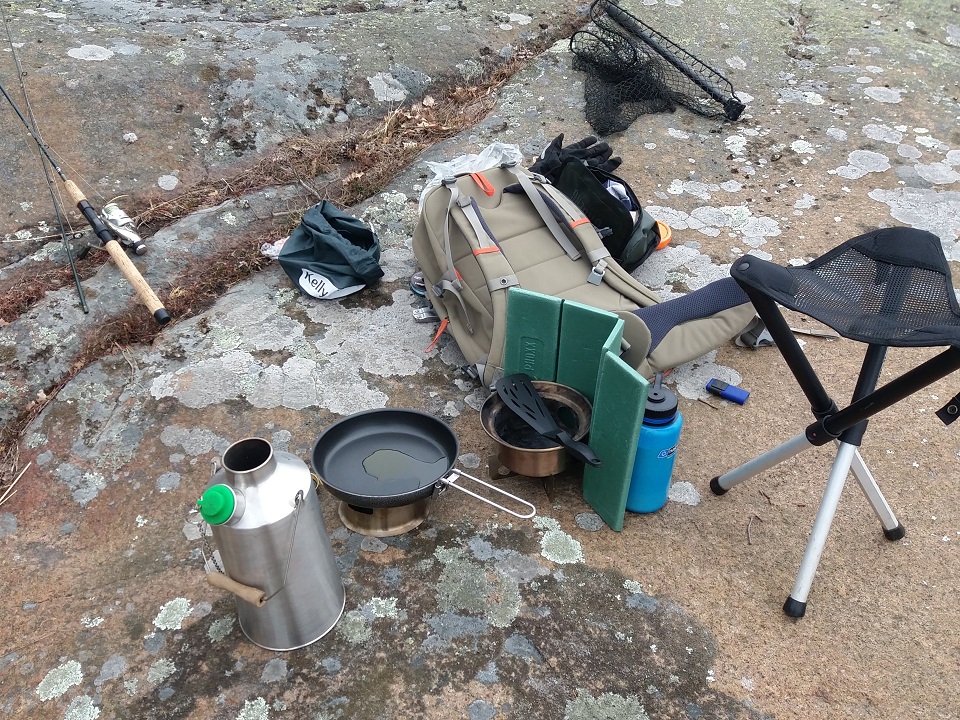 Fishing trip (Sweden). Using hobostove with alcohol burner to make pancakes, and boiling water with Kelly Kettle for coffee and warm dishing water. Pine cones a few feet away as fuel